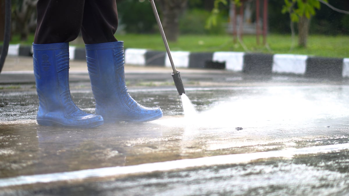 High pressure power washing restoring a concrete driveway surface